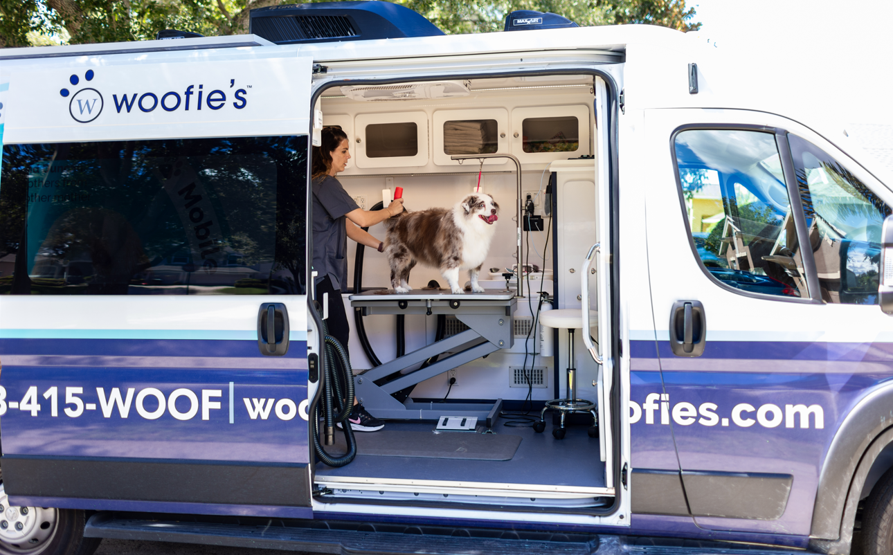 groomer with Australian shepherd inside Woofie's mobile pet spa